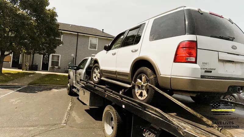 An SUV loaded on a flatbed at an apartment community